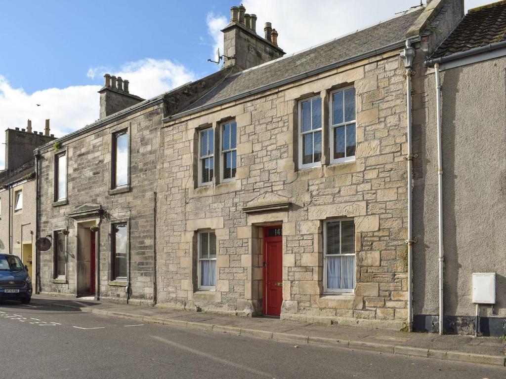 a stone building with a red door on a street at Victorias Haven in Kirkcaldy