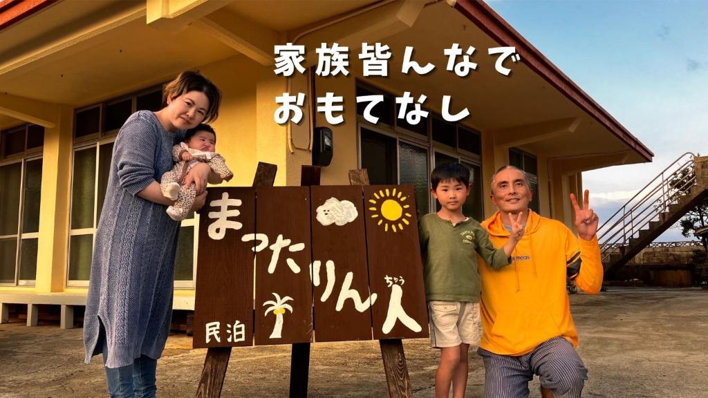Janadōにある民泊まったりん人の看板の横に立つ女と子供二人