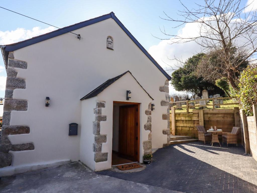 een klein wit huis met een houten deur bij The Old Chapel in Newton Abbot