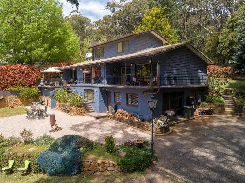 a blue house with a porch and a patio at Sweeping views of Hanging Rock and Cobaw Ranges in Mount Macedon