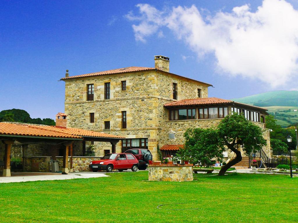 een groot stenen huis met een rode auto ervoor bij Posada Ribera del Pas in Iruz