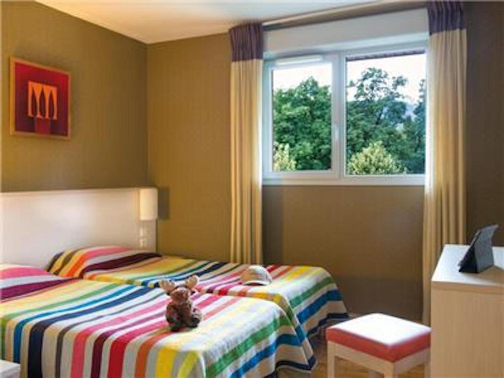 um urso de peluche sentado numa cama num quarto em La Villa Du Lac- 3 rooms for 6 people em Divonne-les-Bains