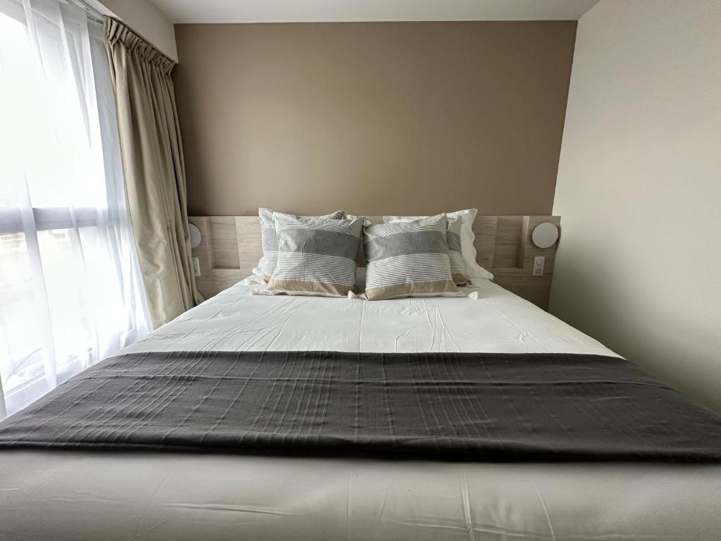 uma cama com lençóis brancos e almofadas num quarto em Hôtel Akena Chauray-Niort em Chauray