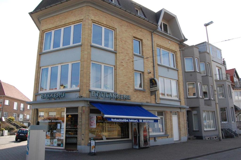 a building on the corner of a street with a store at Westhoek Apartments in De Panne
