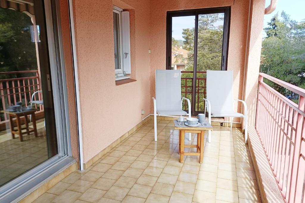 einen Balkon mit zwei Stühlen und einem Tisch darauf in der Unterkunft Spacious sea view apart at 50m from the beach in Bandol