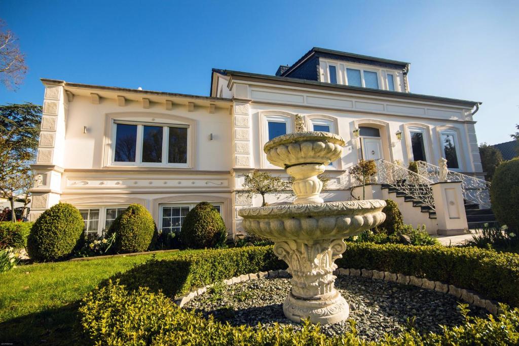 a large house with a fountain in front of it at Villa Rosengarten auf der Sonneninsel Fehmarn in Fehmarn