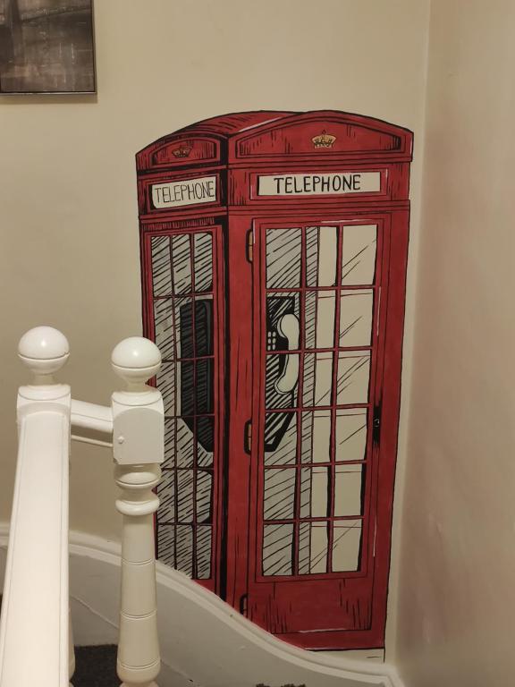 cabina de teléfono roja en la esquina de una habitación en Bright Park Inn, en Peterborough