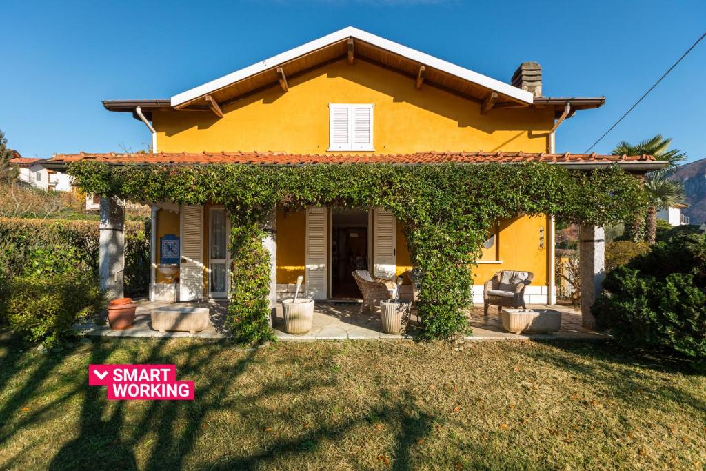 una casa amarilla con un porche cubierto de hiedra en Maison Jaune by Wonderful Italy en Bellagio