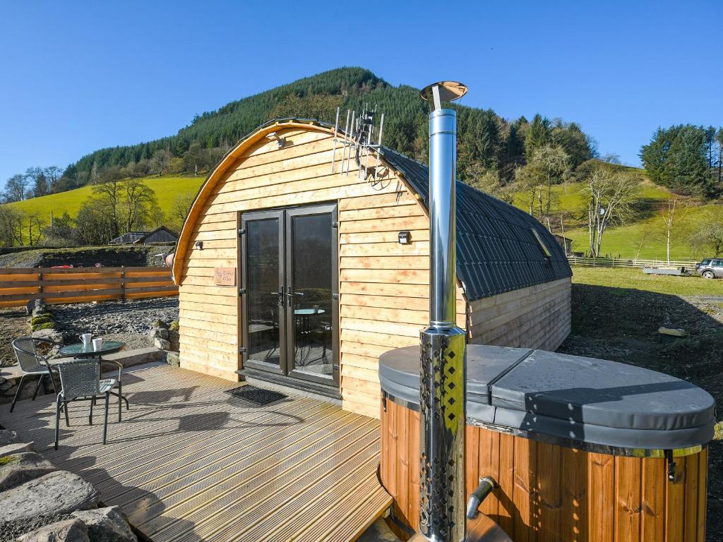 a small wooden cabin with a hot tub and a deck at Creyr Glas Pod -uk41796 in Hirnant