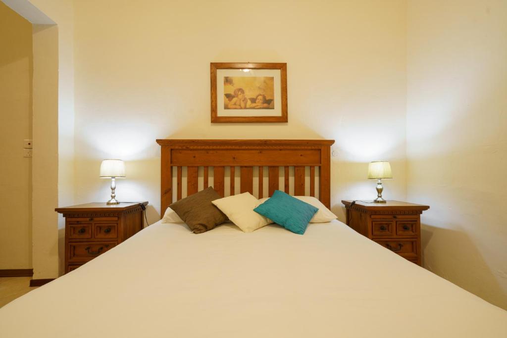 sypialnia z dużym białym łóżkiem z 2 stolikami nocnymi w obiekcie Lantern Stay w mieście Marsalforn