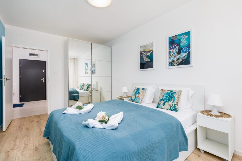 a white bedroom with two towels on a blue bed at Wellness & SPA Resort Aquamarine Apartment by Renters in Dziwnów