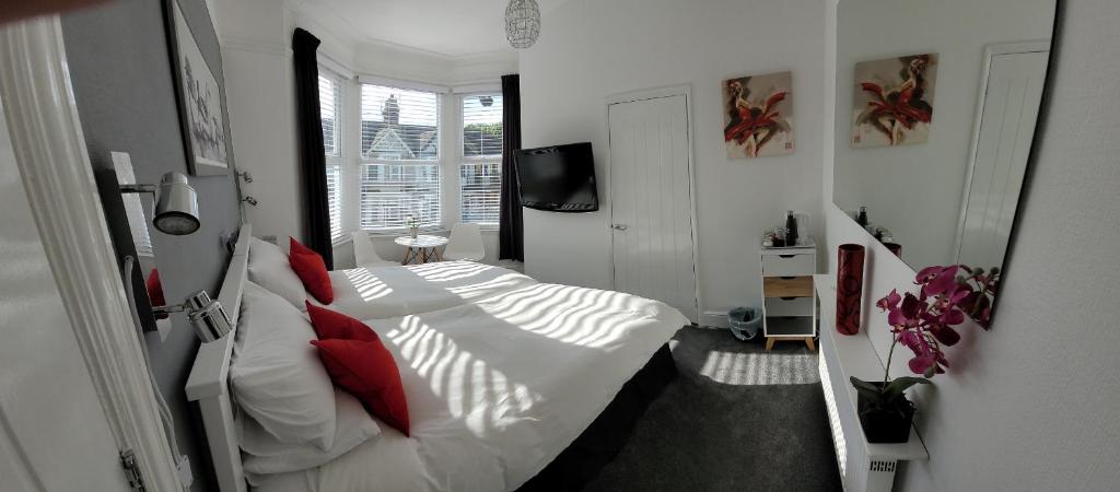 a bedroom with a bed with white sheets and red pillows at Edelweiss Guest House in Southend-on-Sea