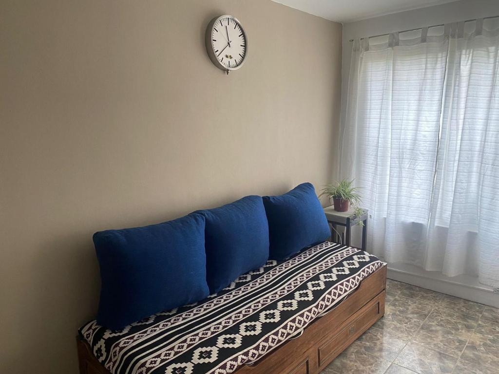 a bedroom with a bed with blue pillows and a clock on the wall at Casa Olive, en complejo residencial con cochera in Godoy Cruz
