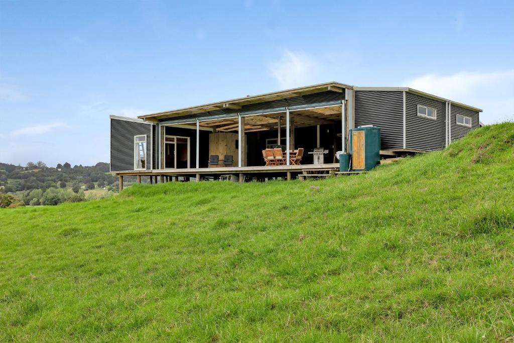 a house on top of a grassy hill at Waimate Farmstay - Kerikeri Holiday Home in Kerikeri