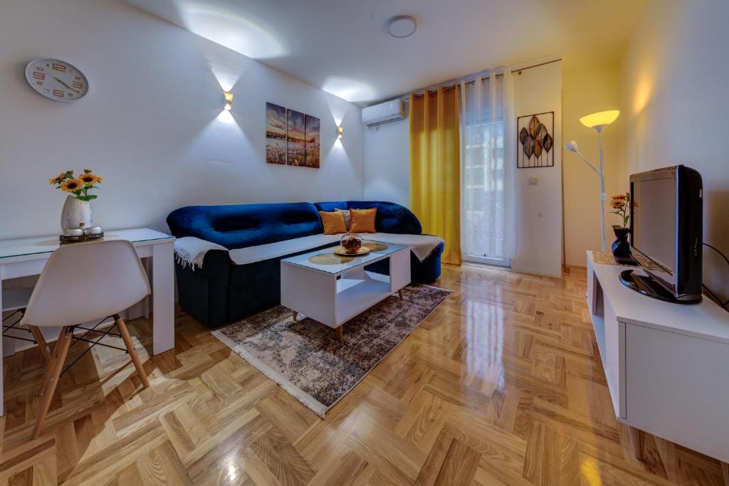 a living room with a blue couch and a tv at Apartment Makao in Podgorica