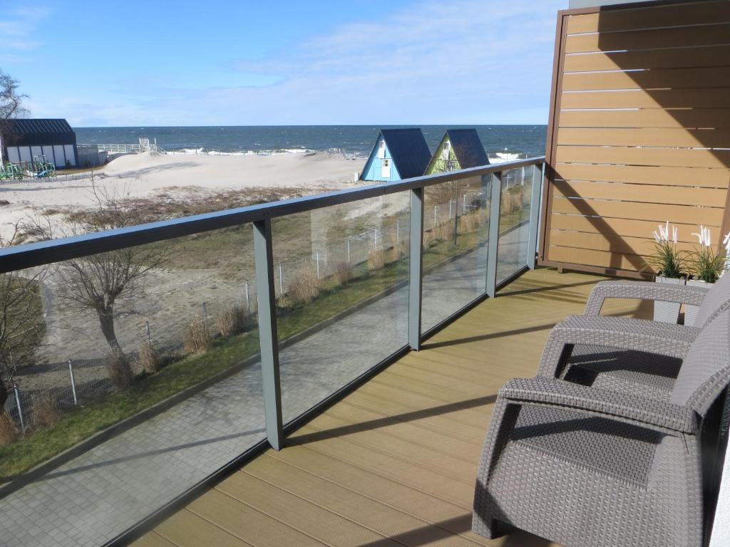 een balkon met 2 stoelen en uitzicht op het strand bij GARDENIA Apartament Przy Plaży 17 in Dziwnów