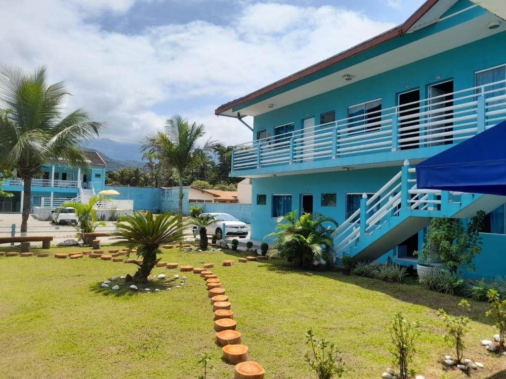 una casa azul con césped delante en Chalés Céu e Mar Ubatuba, en Ubatuba