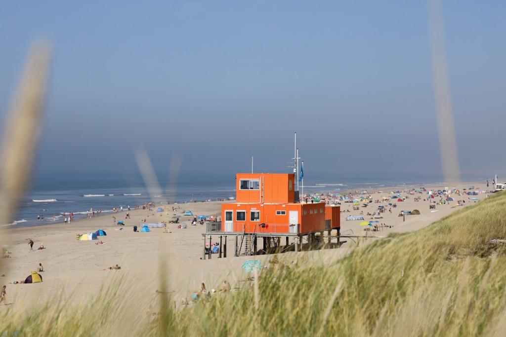 um edifício laranja numa praia com uma multidão de pessoas em Abbestederweg 24A Callantsoog em Callantsoog