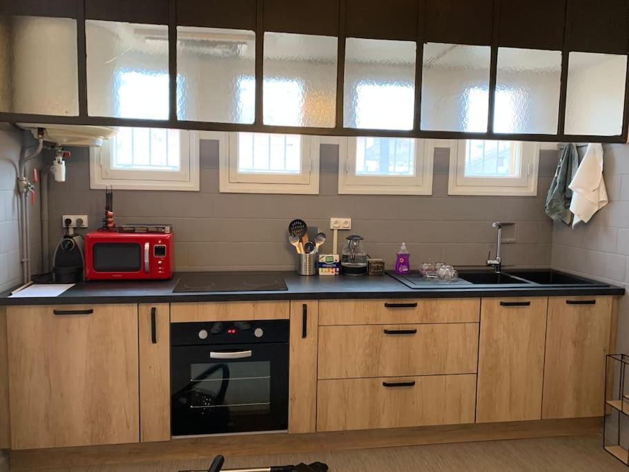 kuchnia z drewnianymi szafkami i czerwoną kuchenką mikrofalową w obiekcie Belle maison 100m2 avec terrasse et parking privé w Béziers