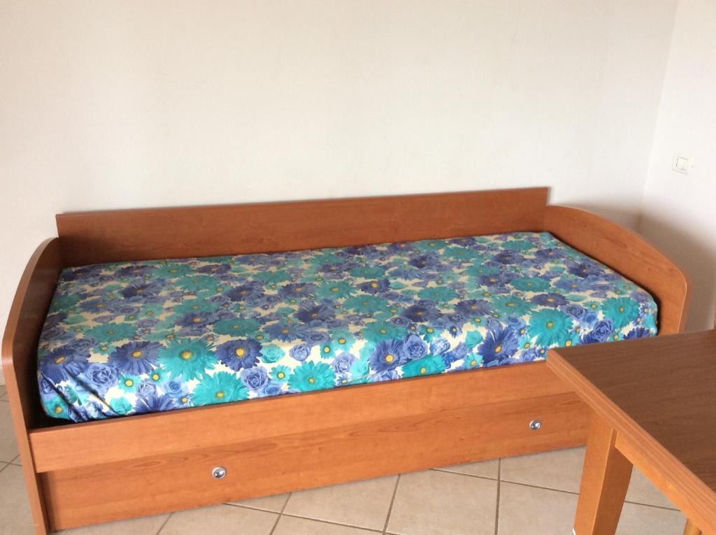 łóżko z drewnianą ramą w pokoju ze stołem w obiekcie Casa Vacanze Residence I delfini w mieście Badesi