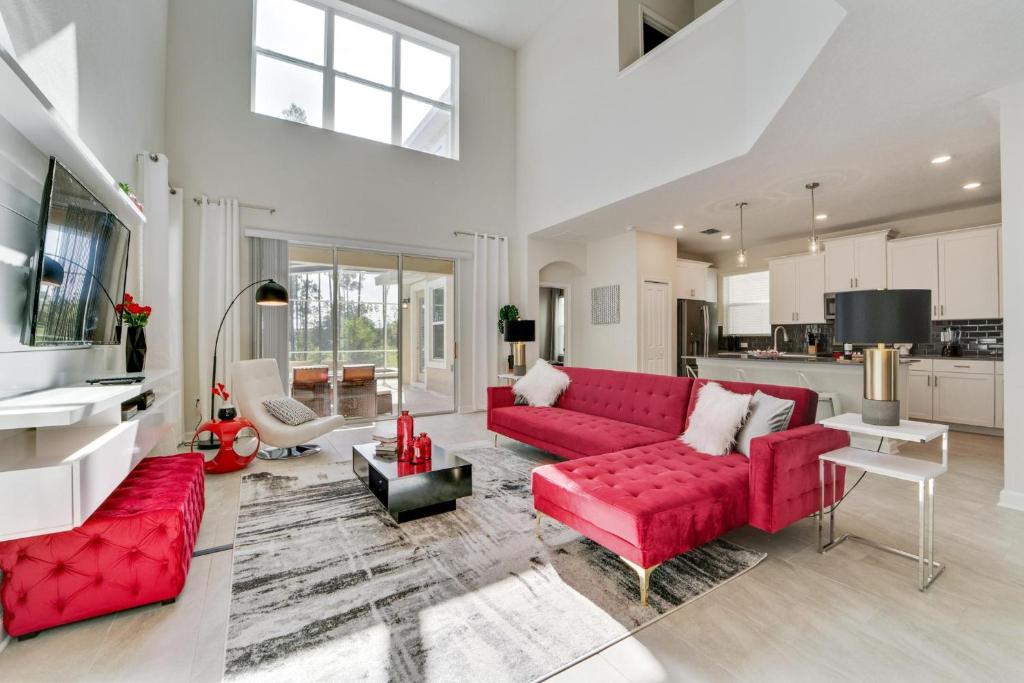 a living room with red couches and a kitchen at Ruby Falls Villa in Kissimmee
