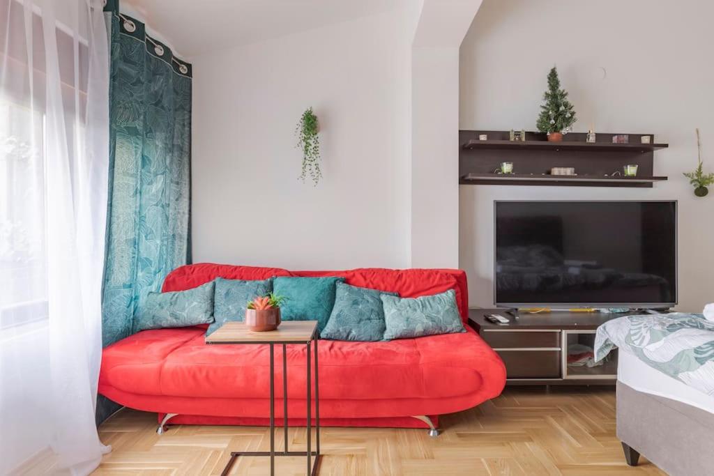 czerwona kanapa w salonie z telewizorem w obiekcie Warm house full of green ambient,joy and comfort w Zagrzebiu
