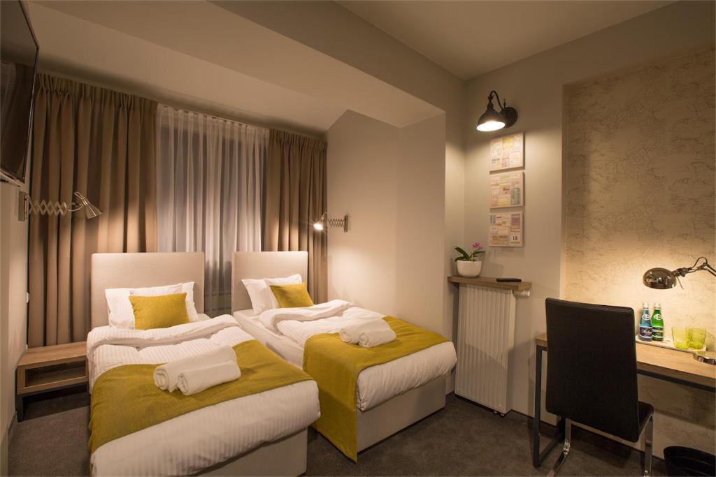 a hotel room with two beds and a desk at MarcoPolo House in Warsaw