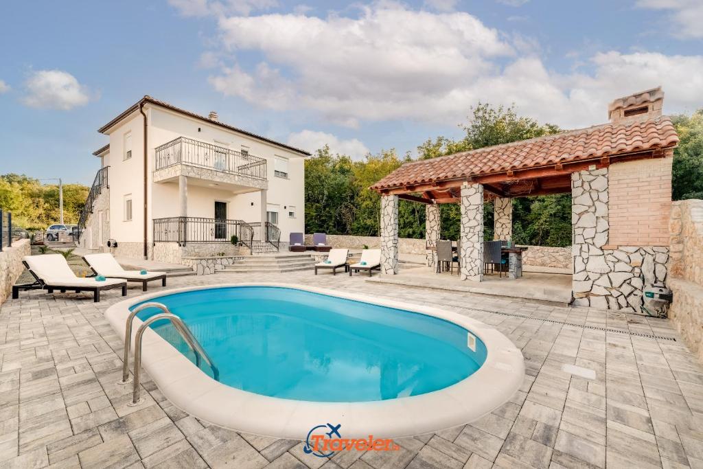 a patio with a swimming pool and a house at Villa Hlapa-new modern villa near beach - by TRAVELER tourist agency Krk in Gostinjac