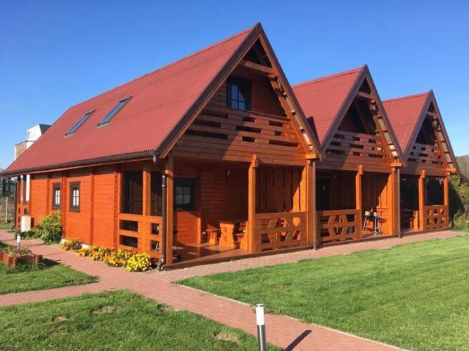 a large wooden cabin with a red roof at Comfortable holiday homes, Mielenko in Mielenko