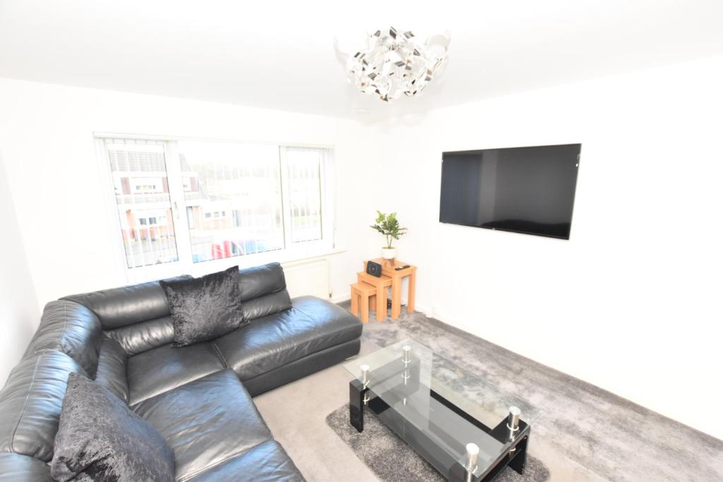 uma sala de estar com um sofá de couro e uma televisão de ecrã plano em 3 Bedroom Apartment in a Quiet Location em Airdrie