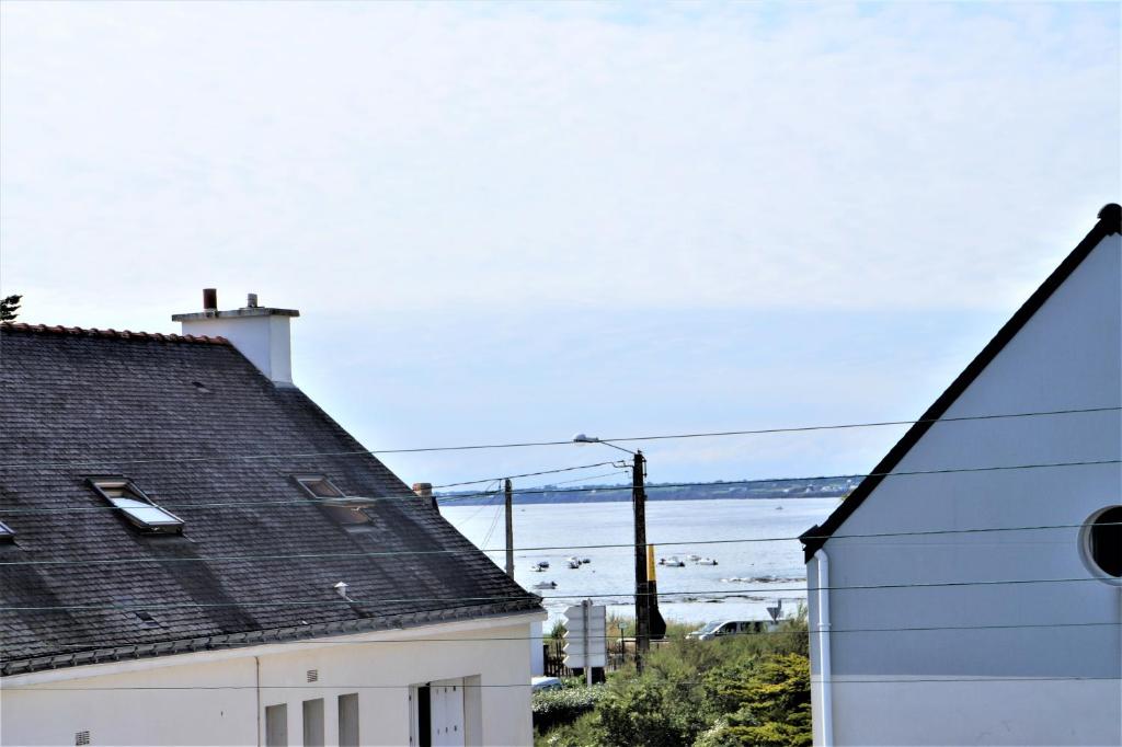 uma vista para o oceano entre duas casas em Appartement 3 pièces 5 à 6 personnes - vue mer - à 200 m de la plage - FANTA em Ploemeur