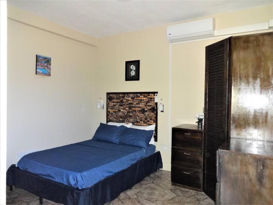 um quarto com uma cama azul e uma cómoda em St. George's Holiday Studio Vacation of a lifetime em Fontenoy