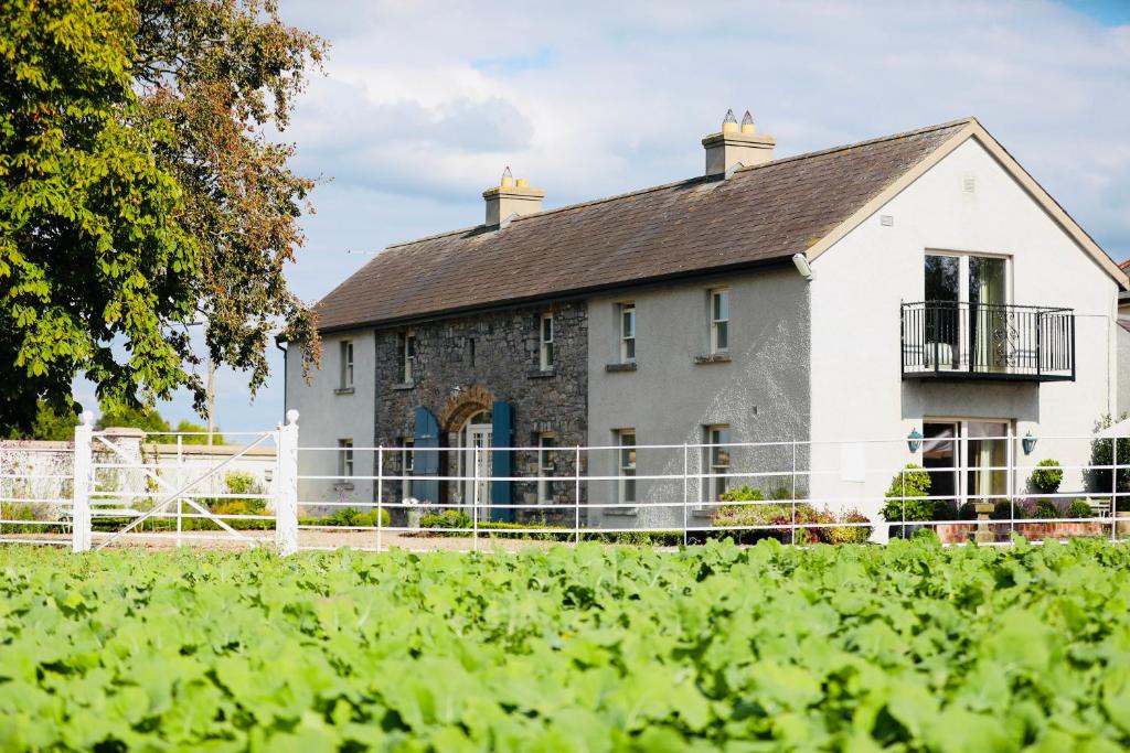 ein weißes Haus mit einem Zaun davor in der Unterkunft The Granary, Luxuriously Restored Barn on a Farm in Thurles