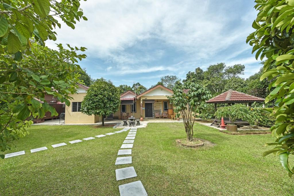 OYO HOME 90692 Tok Babah Village Homestay في Kampong Sungai Mati: حديقة بها مسار أمام المنزل