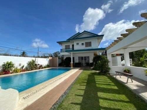 a house with a swimming pool in front of a house at TGT GUEST HOUSE in Tagaytay