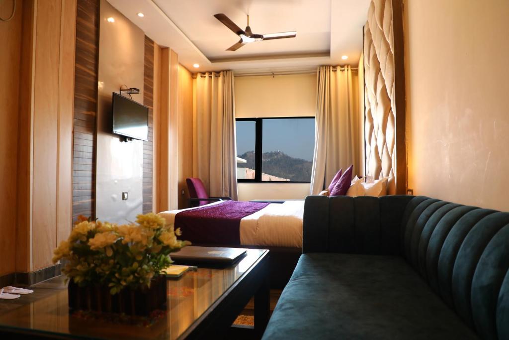 Perfectstayz Premium @Harkipauri Road في حاريدوار: غرفه فندقيه بسرير واريكه