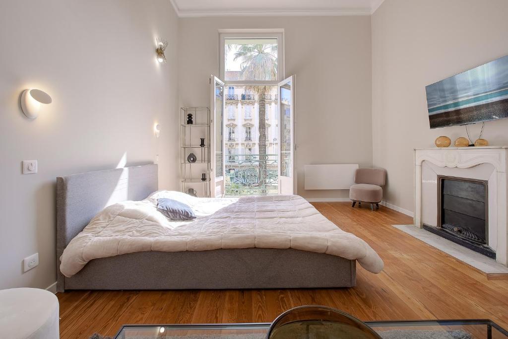 une chambre blanche avec un lit et une cheminée dans l'établissement Maison Bianchi - Clemenceau, à Nice