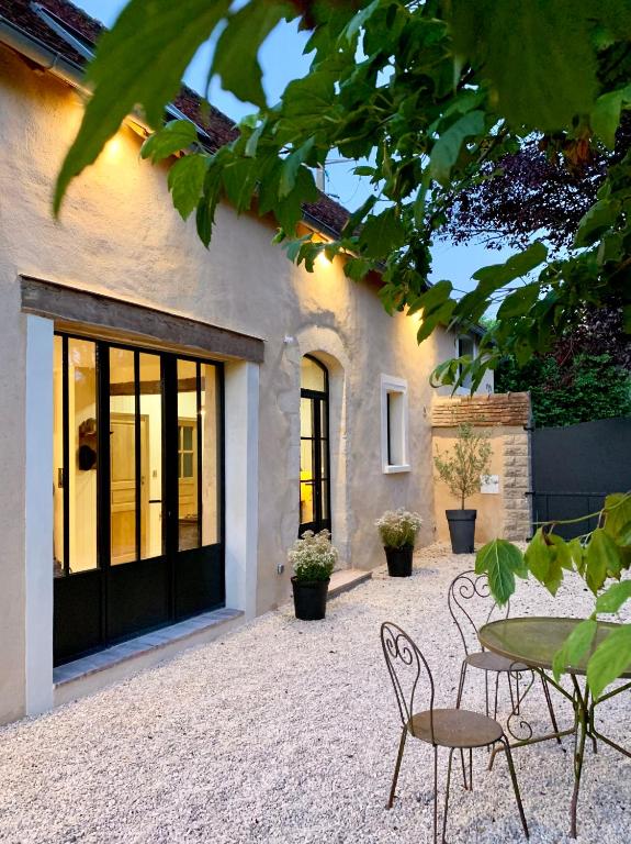 a patio with a table and chairs in front of a building at LA CLEF DES CHAMPS 61 in La Chapelle-Souëf