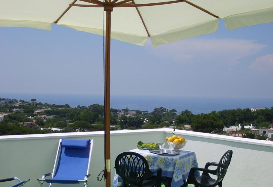 d'une table, de chaises et d'un parasol sur le balcon. dans l'établissement Casa Morgera, à Ischia