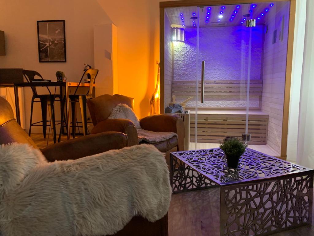 uma sala de estar com um sofá, uma mesa e uma janela em La Clé des Plaisirs em Chambéry