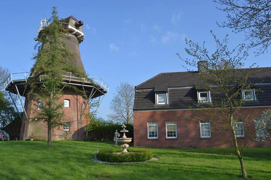 une maison avec une tour et une statue devant elle dans l'établissement Uttumer Mühle, à Krummhörn