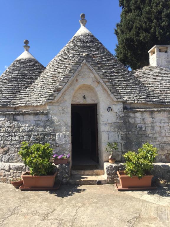 a small stone building with a door and two potted plants at Gasphouse in Castellana Grotte