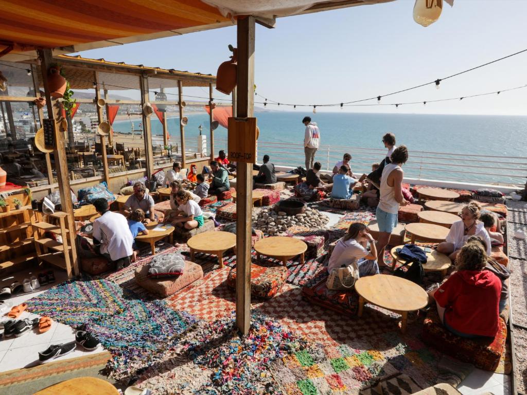un gruppo di persone seduti ai tavoli sulla spiaggia di Locals Taghazout surfcamp a Taghazout