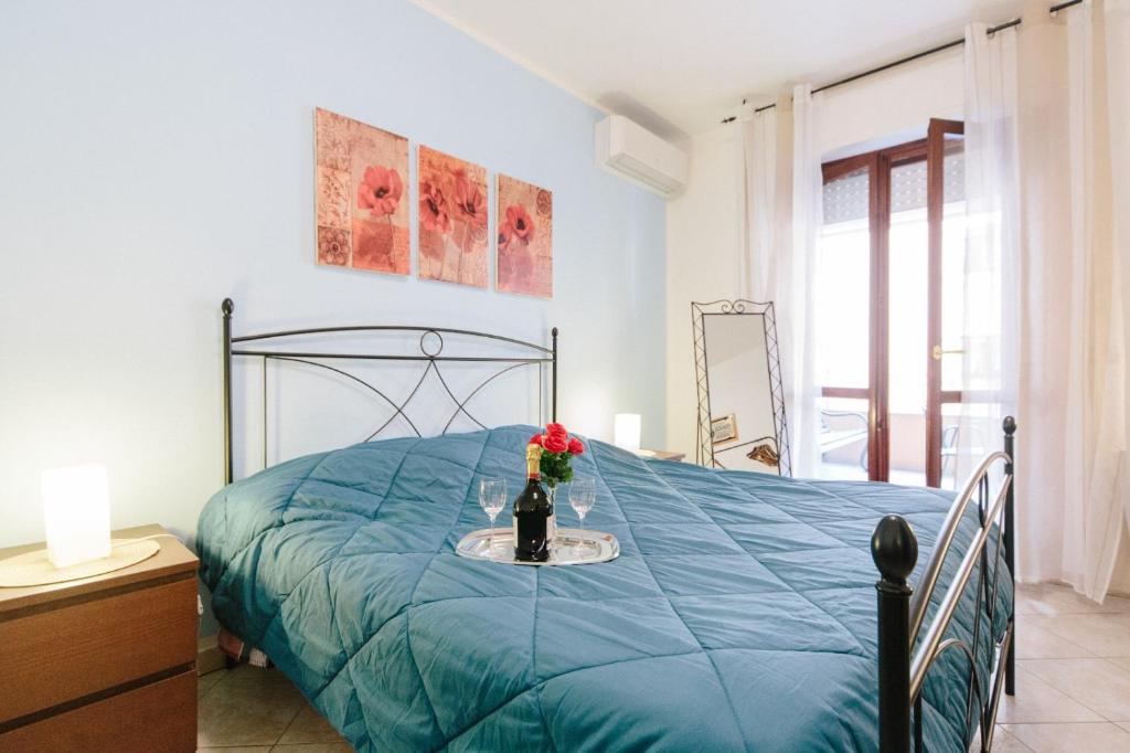 um quarto com uma cama azul com um vaso de flores em Lido Alghero Beach House em Alghero