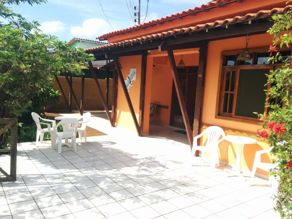 un patio con sedie e tavoli bianchi di fronte a una casa di Pousada Mabuya a Fernando de Noronha