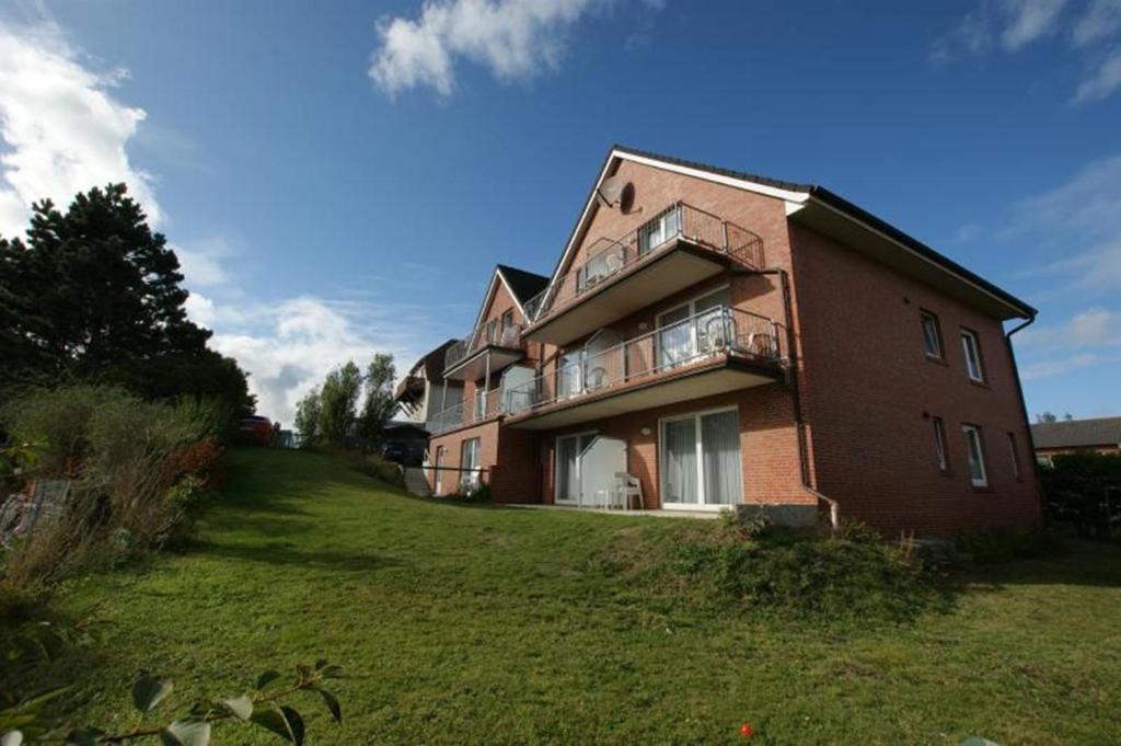 ein großes Backsteinhaus auf einem grasbewachsenen Hügel in der Unterkunft Haus Königsdüne II/7 in Borkum