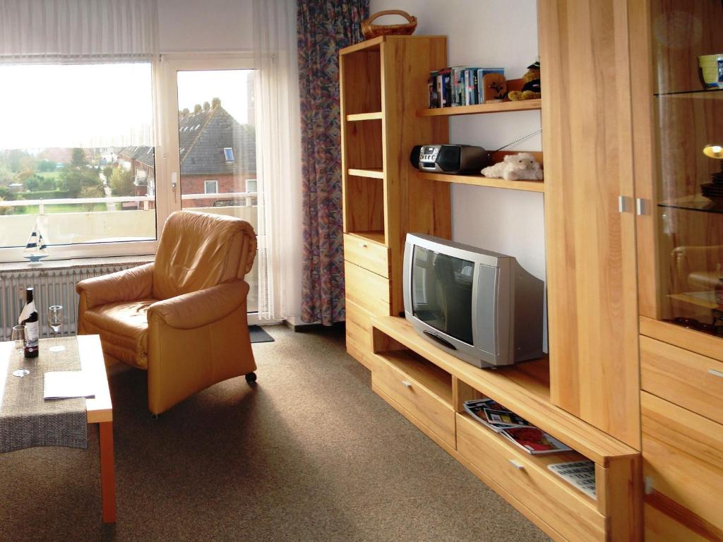 a living room with a television and a chair at Olde-Baas in Borkum