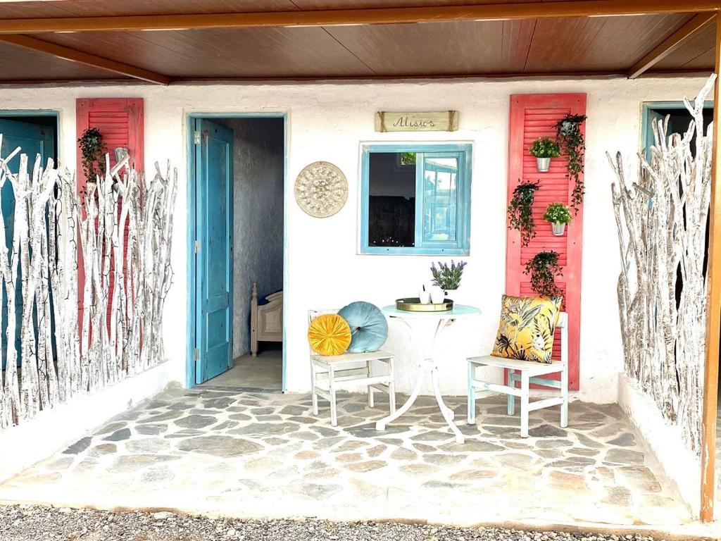 un porche con mesa y sillas frente a una puerta en Alisios HOT TUB sauna piscina y naturaleza, en Buzanada