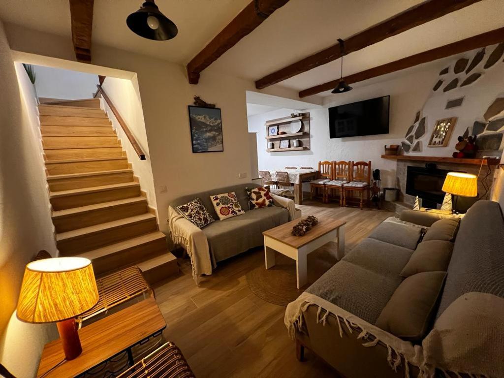 ein Wohnzimmer mit einem Sofa und einer Treppe in der Unterkunft Casa Rural El cerrillo in Abrucena