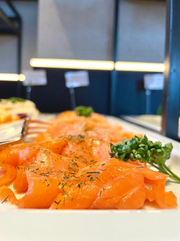 a plate of food with salmon and greens on it at Bergdorf Hotel Zaglgut in Kaprun